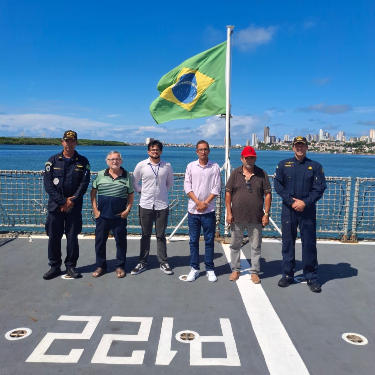 Foto da equipe com os comandantes do navio no heliponto